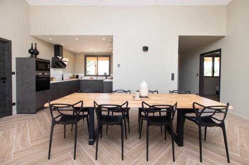 a kitchen and dining room with a wooden table and chairs at La Villa face au Lac in Saramon