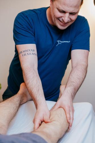 a man in a blue shirt standing on a bed with his hands on his leg at Aqua Blu Hotel in Bad Füssing