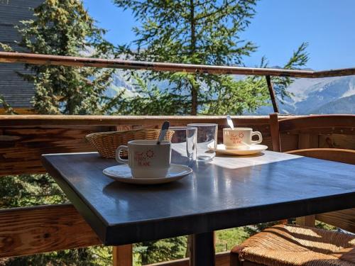 une table bleue avec deux tasses et des assiettes dessus dans l'établissement Maxi Studio 6 pers, 20m des pistes, proche commerces, sports à pied - FR-1-262-98, à Forest des Baniols