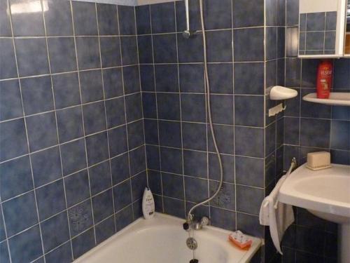 La salle de bains est pourvue de carrelage bleu, d'une baignoire et d'un lavabo. dans l'établissement Appartement T2 avec Piscine, Ascenseur et Parking Privé, à 300m de la Plage - 4 Couchages, Animaux OK - FR-1-388-89, à Argelès-sur-Mer