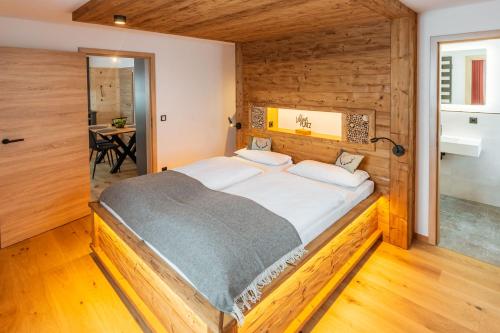 Cama grande en habitación con paredes de madera en Zugspitze Apartment GLÜCK.AUF en Waldidylle