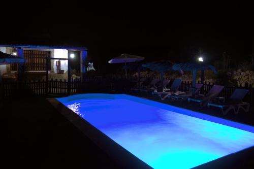a swimming pool at night with chairs and umbrellas at CASA RURAL PRIVADA El ASIENTO LOS GEMELOS in Pruna