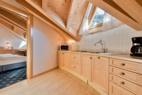 una cocina con armarios de madera y una gran ventana en Garnì La Dorada, en Colfosco