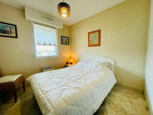 une chambre avec un lit blanc et une fenêtre dans l'établissement Quiberon : Joli T2 avec Balcon Sud, Proche Plage et Centre-Ville - FR-1-478-255, à Quiberon