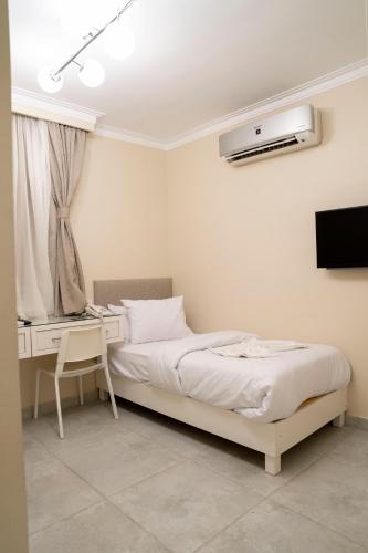 a bedroom with a bed and a desk and a television at Dream House in 6th Of October