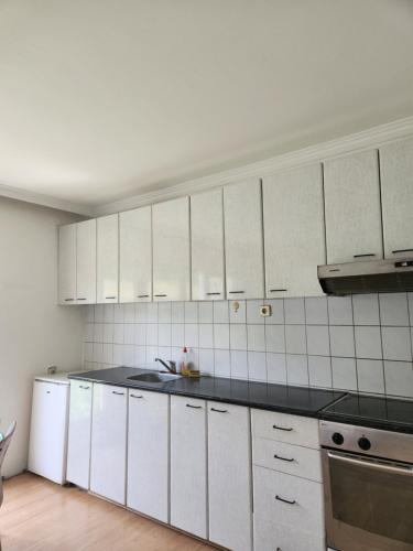 uma cozinha com armários brancos e um balcão preto em House ViS em Dimitrovgrad