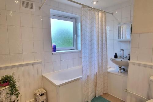 a bathroom with a tub and a sink and a window at Large Duplex in Bermondsey in London