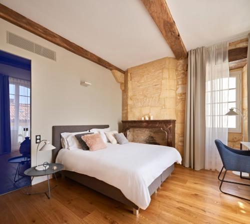 1 dormitorio con 1 cama grande y chimenea en hideauts hotels Le Chevalier bleu, en Monpazier