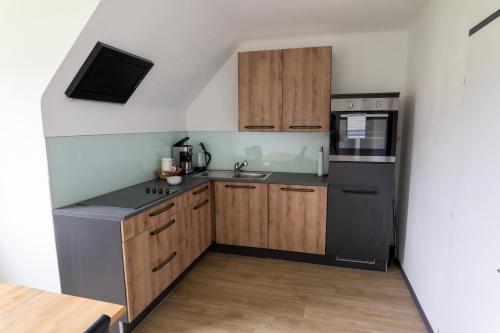 eine Küche mit Holzschränken und einem schwarzen Kühlschrank in der Unterkunft Glöcknerhaus in Sankt Gallen