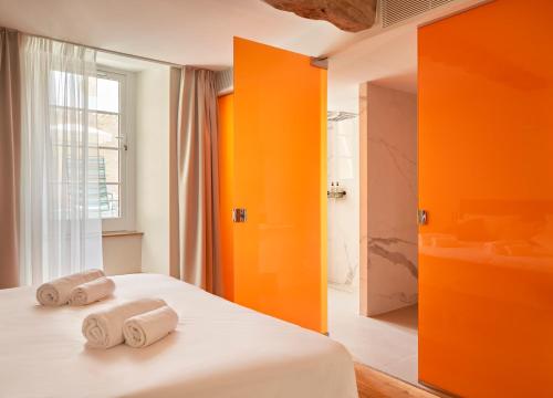 a bedroom with orange walls and a bed with two towels at hideauts hotels Le Chevalier bleu in Monpazier