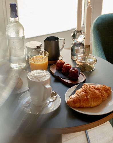een tafel met een ontbijt van koffie, croissants en drankjes bij Hotel Le Chevalier Bleu in Monpazier