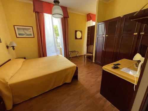 a hotel room with a bed and a dresser in it at Hotel Rosalia in Bordighera