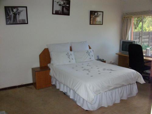 OlifantsfonteinにあるPalesa Guesthouseの白いベッド、デスク、コンピュータが備わるベッドルーム1室が備わります。