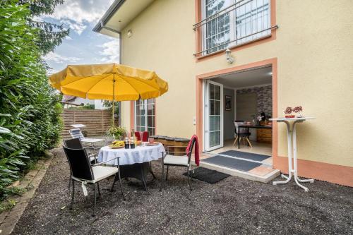 um pátio com uma mesa e um guarda-chuva amarelo em Ferienwohnung For two em Mahlberg
