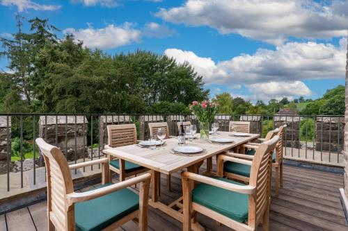 eine Holzterrasse mit einem Holztisch und Stühlen in der Unterkunft Lower Lodge Gatehouse at Kentchurch 