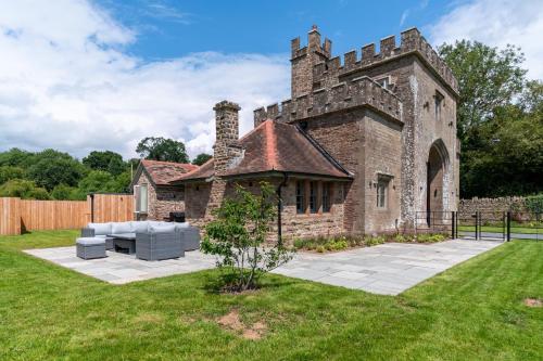 ein altes Steingebäude mit einer Couch im Hof in der Unterkunft Lower Lodge Gatehouse at Kentchurch 