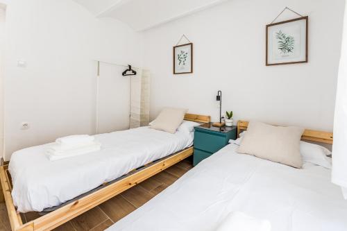 Habitación con 2 camas, paredes blancas y suelo de madera. en Apartamento en CENTRO CIUDAD, en El Puerto de Santa María