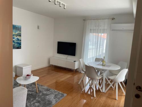 uma sala de estar branca com uma mesa e uma televisão em Apartman SeaSide em Zadar