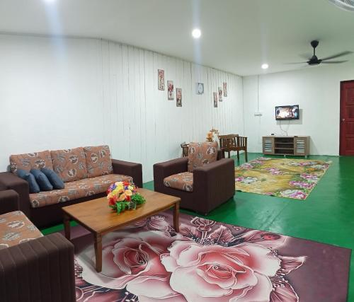 Bandar  Pusat JengkaにあるHomestay Bakti @Rantau Perintisのリビングルーム(ソファ、テーブル、花付)