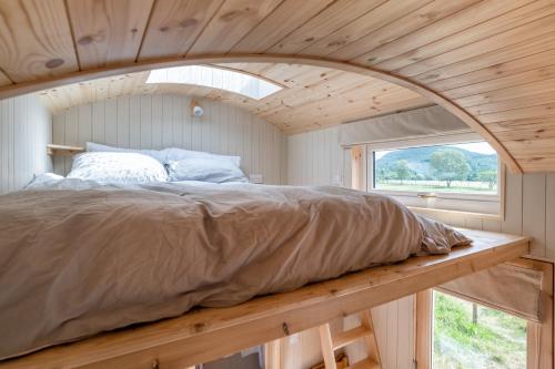 Łóżko w małym pokoju z oknem w obiekcie Enchanting Tiny House with wood burner and hot tub in Cairngorms w mieście Ballater
