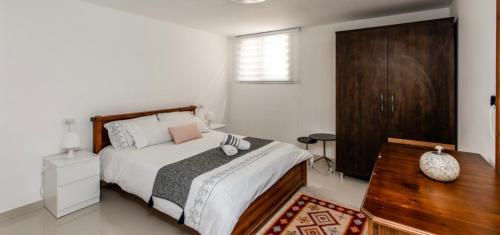 1 dormitorio con cama y tocador de madera en הבית בחורשה, en Zikhron Ya‘aqov