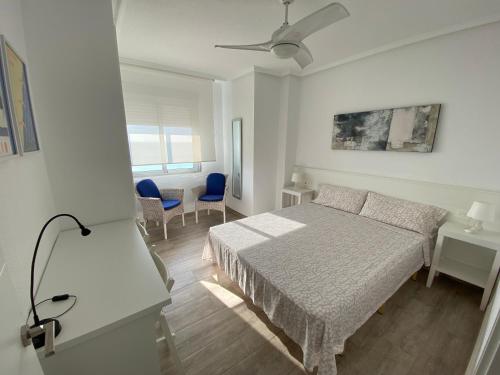 a white bedroom with a bed and a ceiling fan at Emilia's Cabin in Guardamar del Segura