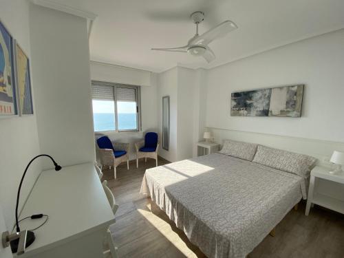 een witte slaapkamer met een bed en een tafel en stoelen bij Emilia's Cabin in Guardamar del Segura