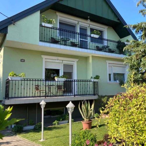 a green house with a balcony and plants at Holiday home in Gyenesdias - Balaton 40755 in Gyenesdiás