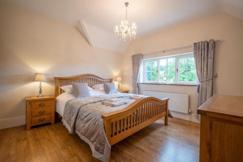 a bedroom with a bed and a window and a chandelier at Mellowstones in Ebrington