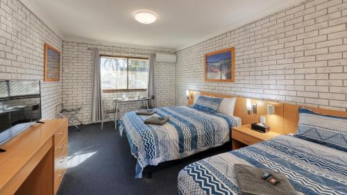 una camera d'albergo con due letti e una televisione di The Major Mitchell Motel a Bourke