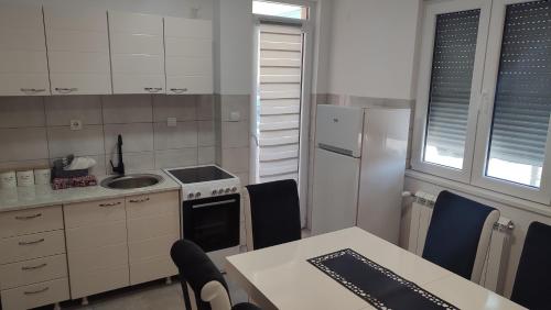 a kitchen with a white refrigerator and a table with chairs at Black and White in Pirot