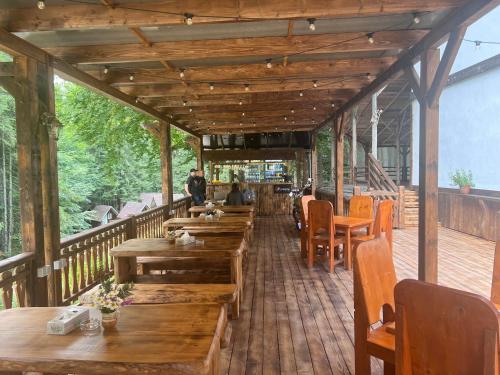 um restaurante com mesas e cadeiras de madeira num deque em Barlogul din Vidraru em Curtea de Argeş