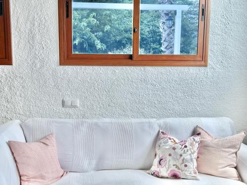 a white couch with pillows sitting under a window at Villa Only Adults 2 Pax · Piscina Privada · A/C · WIFI · BBQ in Blanes