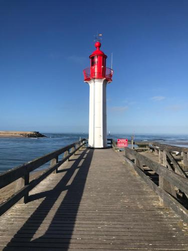 a red and white lighthouse sitting on a pier at La Maison Rouge in Trouville-sur-Mer