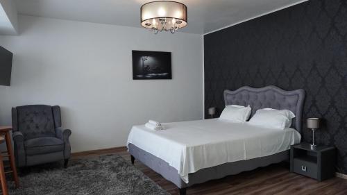a bedroom with a bed and a chair and a chandelier at Luxury 1BR studio near Hanul Drumetului Bucharest in Bucharest