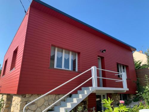 a red house with stairs leading up to it at La Maison Rouge in Trouville-sur-Mer