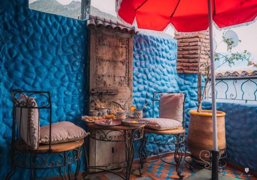 niebieski pokój ze stołem, krzesłami i parasolem w obiekcie Riad Azurite w mieście Szafszawan