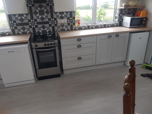 a kitchen with white cabinets and a stove top oven at Fully Refurbished 200-Year-Old Farmhouse in Tralee