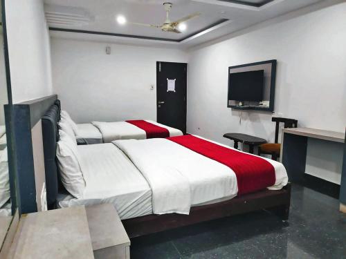 a bedroom with two beds and a flat screen tv at STAYMAKER Hotel Hill View in Madikeri