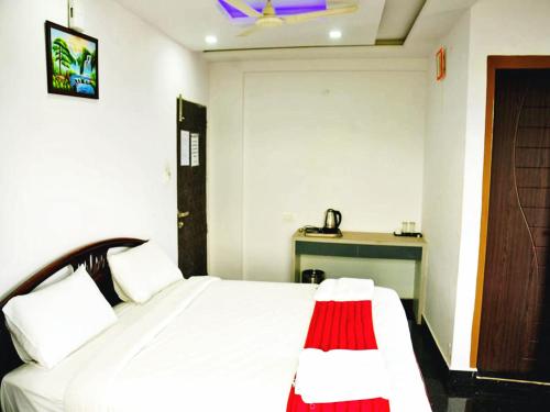 a bedroom with a white bed and a desk at STAYMAKER Hotel Hill View in Madikeri