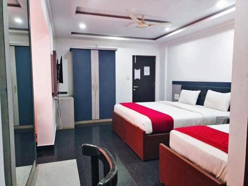 a hotel room with two beds and a ceiling fan at Hotel Hill View in Madikeri