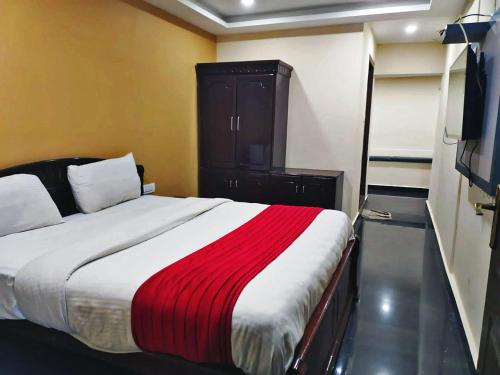 a bedroom with a bed with a red and white blanket at Hotel Hill View in Madikeri