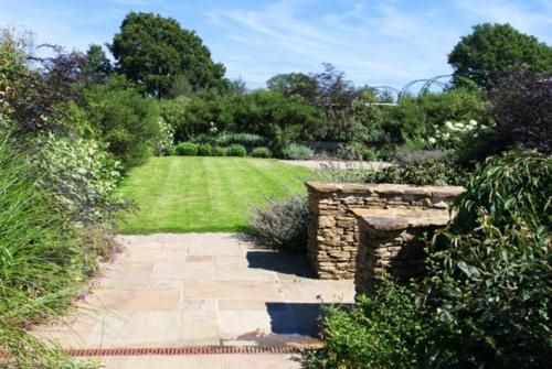 a garden with a stone wall and a lawn at Horsham-Gatwick 16 miles Luxury-near Leonardslee in Horsham