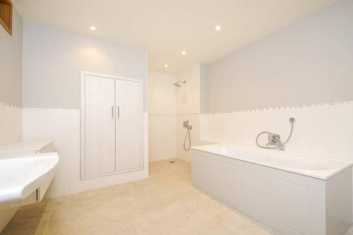 ein weißes Badezimmer mit einer Badewanne und einem Waschbecken in der Unterkunft Horsham-Gatwick 16 miles Luxury-near Leonardslee in Horsham