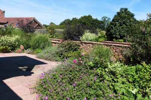 a garden with pink flowers and a stone wall at Horsham-Gatwick 16 miles Luxury-near Leonardslee in Horsham