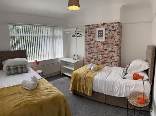 a bedroom with two beds and a brick wall at Boss Fab4 Stay &Garden Pro Host in Liverpool