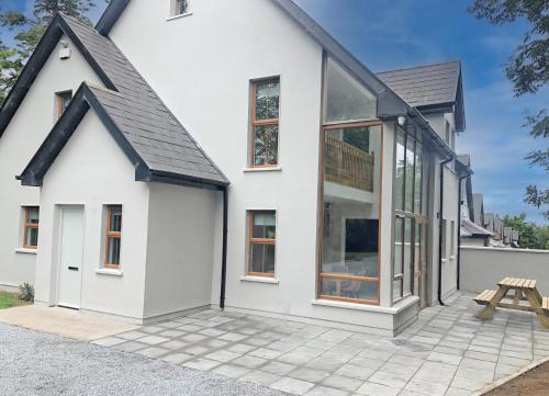a white house with large windows and a picnic table at Old Court Holiday Homes Terryglass 4 Bed No 12 by Trident Holiday Homes in Terryglass