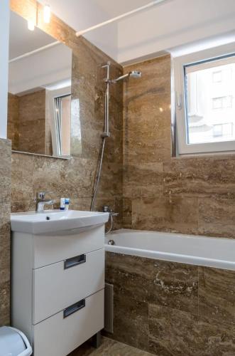 a bathroom with a sink and a bath tub at Luxury Apartments Newton by GLAM in Iaşi