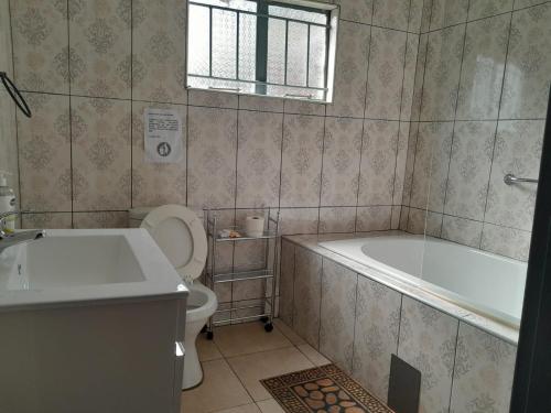 a bathroom with a tub and a toilet and a sink at RS GARDEN GUESTHOUSE in Thohoyandou