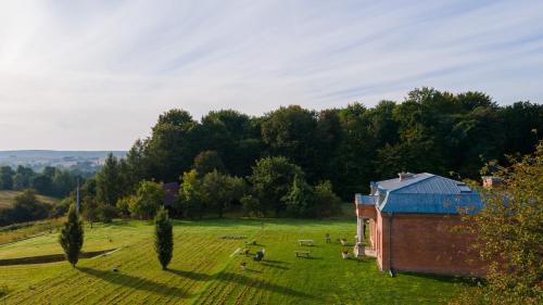 盧布林地區托馬舒夫的住宿－Dworek Atrium，一座有树木的田野上的红色小建筑